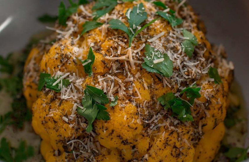 Whole Roasted Cauliflower up close with fresh parsley